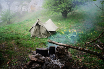 Two camp kettles at the stake early in the morning, tent in the background