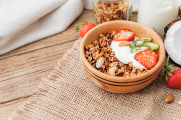 Granola with Greek yoghurt and fruit on a wooden background in a rustic style