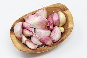 Garlic cloves in olive wood bowl,  on white background.