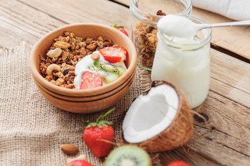 Fototapeta na wymiar Granola with Greek yoghurt and fruit on a wooden background in a rustic style