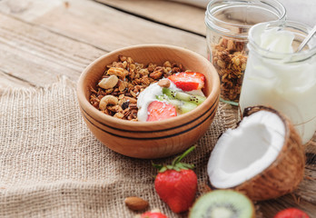 Granola with Greek yoghurt and fruit on a wooden background in a rustic style