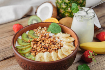 Granola with Greek yoghurt and fruit on a wooden background in a rustic style