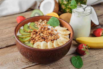 Granola with Greek yoghurt and fruit on a wooden background in a rustic style