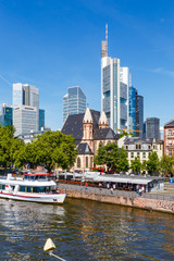 Fototapeta na wymiar Frankfurt am Main. Blick vom Eisernen Steg auf die Skyline und die Schiffsanlegestelle. In der Mitte die St. Leonhardskirche. Mai 2017.