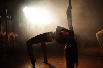 Obraz na płótnie Canvas Young sexy woman exercise pole dance on a dark background