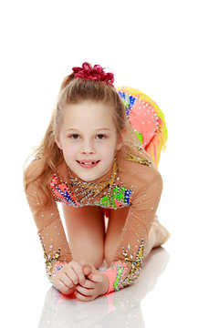 Beautiful girl gymnast sitting on the floor.