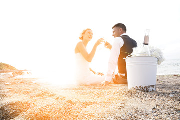 Bride and groom cheering with champagne on the beach