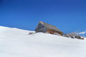 Wooden shelter on the snowy mountain with blue sky.