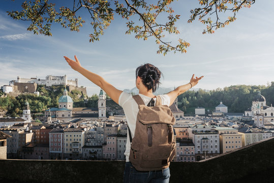 Austria. Salzburg. A young tourist girl with arms raised and admiring looks at the historic city center of Salzburg World Cultural Heritage UNESCO