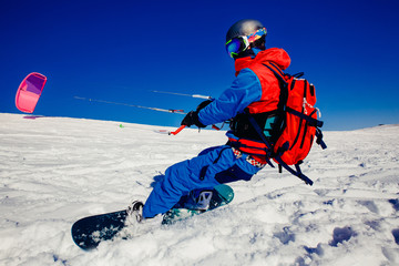 Snowboarder with a kite on fresh snow in the winter in the tundra of Russia against a clear blue sky. Teriberka, Kola Peninsula, Russia. Concept of winter sports snowkite.