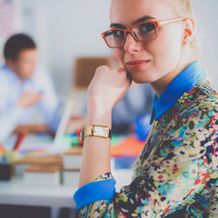 Young attractive female fashion designer working at office desk