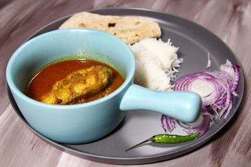 Kerala fish curry on a platter made with coconut and tamarind paste tempered with mustard seeds and fenugreek seeds, selective focus