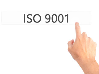 ISO 9001 - Hand pressing a button on blurred background concept on visual screen.
