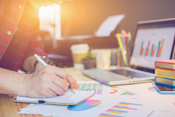 Male manager putting his ideas and writing business plan at workplace,man holding pens and papers, making notes in documents, on the table in office,vintage color,morning light ,copy space