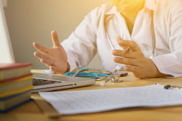 Doctor and patient are discussing something, just hands at the table,explaining prescription to victim,stethoscope and laptop computer on desk in hospital healthcare and medical insurance concept