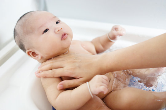 Baby bath time concept,portrait of a baby is being bathed by his mother using tub at home,selective focus.