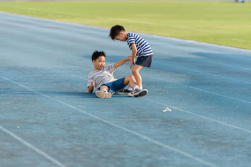 Boy help each other on blue track after fall