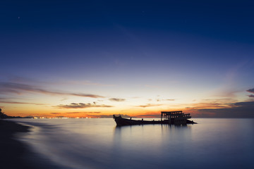 Abandoned shipwreck of wood fishing boat on beach at Twilight time