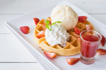 side view shot of delicious ice cream on waffle and strawberry with white plate