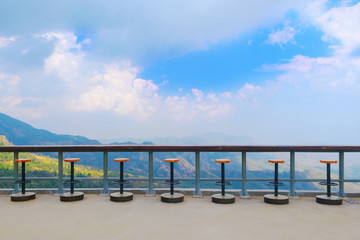 Obraz premium Multi steel bar chair and solid wooden desk bar on natural, blue sky, cloud background for concepts of slow life, relax and green idea.