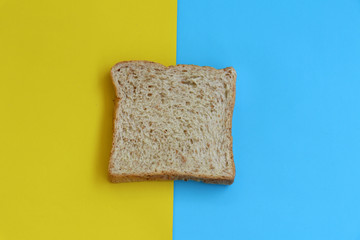 Bread sheet on yellow and blue paper background. minimal food concept.