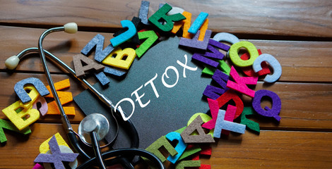 Black board written with " DETOX " and stethoscope on wooden back ground.Image with selective focus.Medical and health care concept