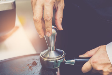 Fototapeta na wymiar Hand of barista using tamper to press ground coffee into portafilter in cafe for prepare to make espresso coffee.