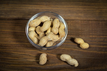 Peanuts with shell in the bowl  on wooden background