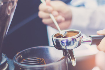 Obraz na płótnie Canvas Hand of barista using tamper with ground coffee into portafilter in cafe for prepare to make espresso coffee.