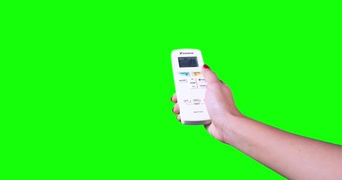 Woman hand turn on the air conditioner with a remote control, shot with green screen background. Shot in 4k resolution