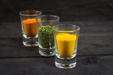 Spices in glasses on a wooden background