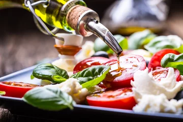 Fotobehang Caprese Salad.Mediterranean salad. Mozzarella cherry tomatoes basil and olive oil on old oak table. Italian cuisine. © weyo