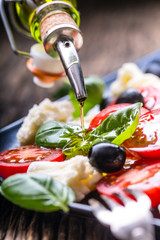 Caprese Salad.Mediterranean salad. Mozzarella cherry tomatoes basil and olive oil on old oak table....