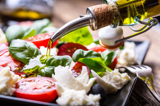 Caprese Salad.Mediterranean salad. Mozzarella cherry tomatoes basil and olive oil on old oak table. Italian cuisine.