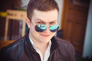 Fototapeta na wymiar Lifestyle young man student in blue sunglasses walk around European streets