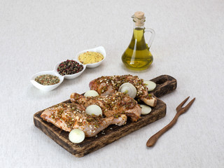 Chicken legs in marinade with olive oil on a wooden board. 