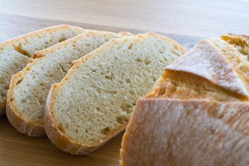 Slices and loaf of bread on wooden table.