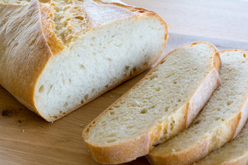 Slices and loaf of bread on wooden table.