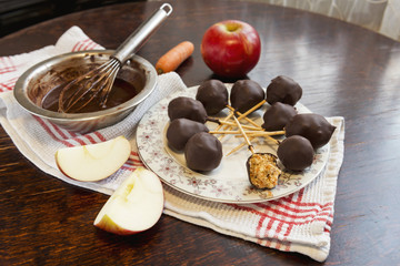 Healthy raw apple and carrot candies on sticks in raw chocolate