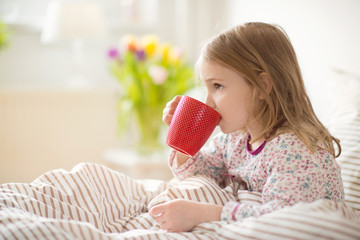 Pretty sick little child girl laying in bed drink tea