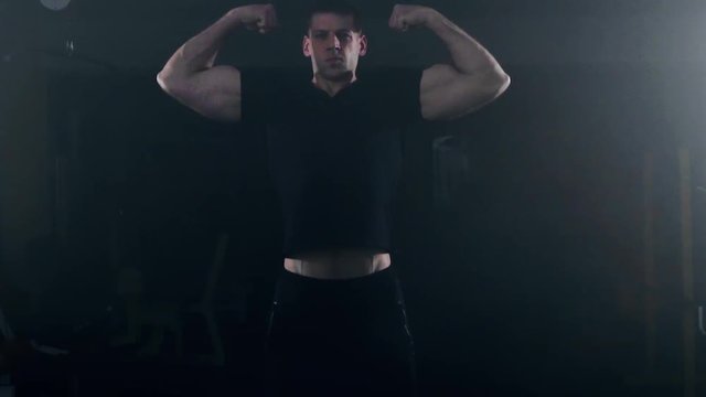 bodybuilder flexing his muscles in gym, dark smoky background