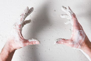 Repair background. Worker dirty hands hold something on white plaster surface, flat lay, void. Building backdrop with free space for advertisement or commercial