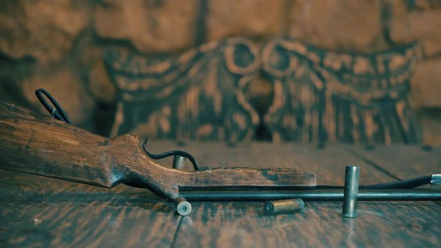 Old hunting rifle lies on the table. On the table are shells and cartridges (warm color)