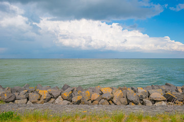 Dike of basalt stones along a lake in spring