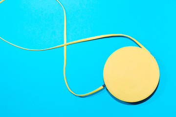 Round yellow cross body bag on a colorful blue background