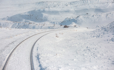 Fototapeta na wymiar Deep Winter Train Tracks with lone tree and Mountains