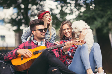 Fototapeta premium Friends in the park having fun playing guitar