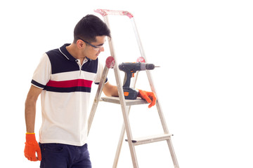 Young man with electric screwdriver and ledder