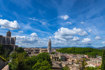 Fototapeta na wymiar Girona old town view with green mountains and blue sky with clouds