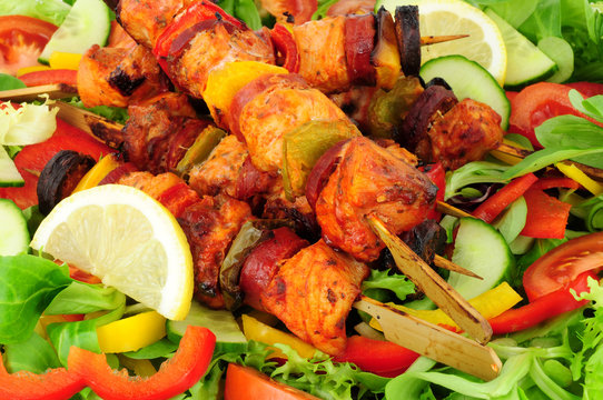 Chicken and spicy chorizo sausage kebabs with sweet peppers on a salad background